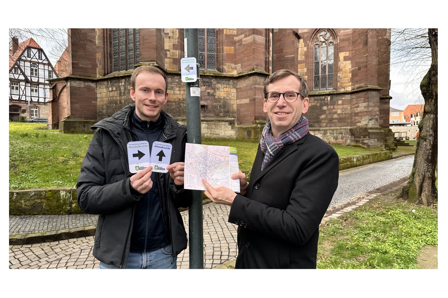 Bildunterzeile: Touristiker Lucas Lambracht (von links) und Bürgermeister Tobias Scherf präsentieren die neuen Wege-Markierung und den überarbeiteten Flyer der Tour der Sehenswürdigkeiten an der Neust