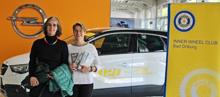 Pastpräsidentin Melanie Humborg, Präsidentin Petra Nolte im Autohaus Humborg vor einem Fahrzeug Opel und dem Logo Inner Wheel