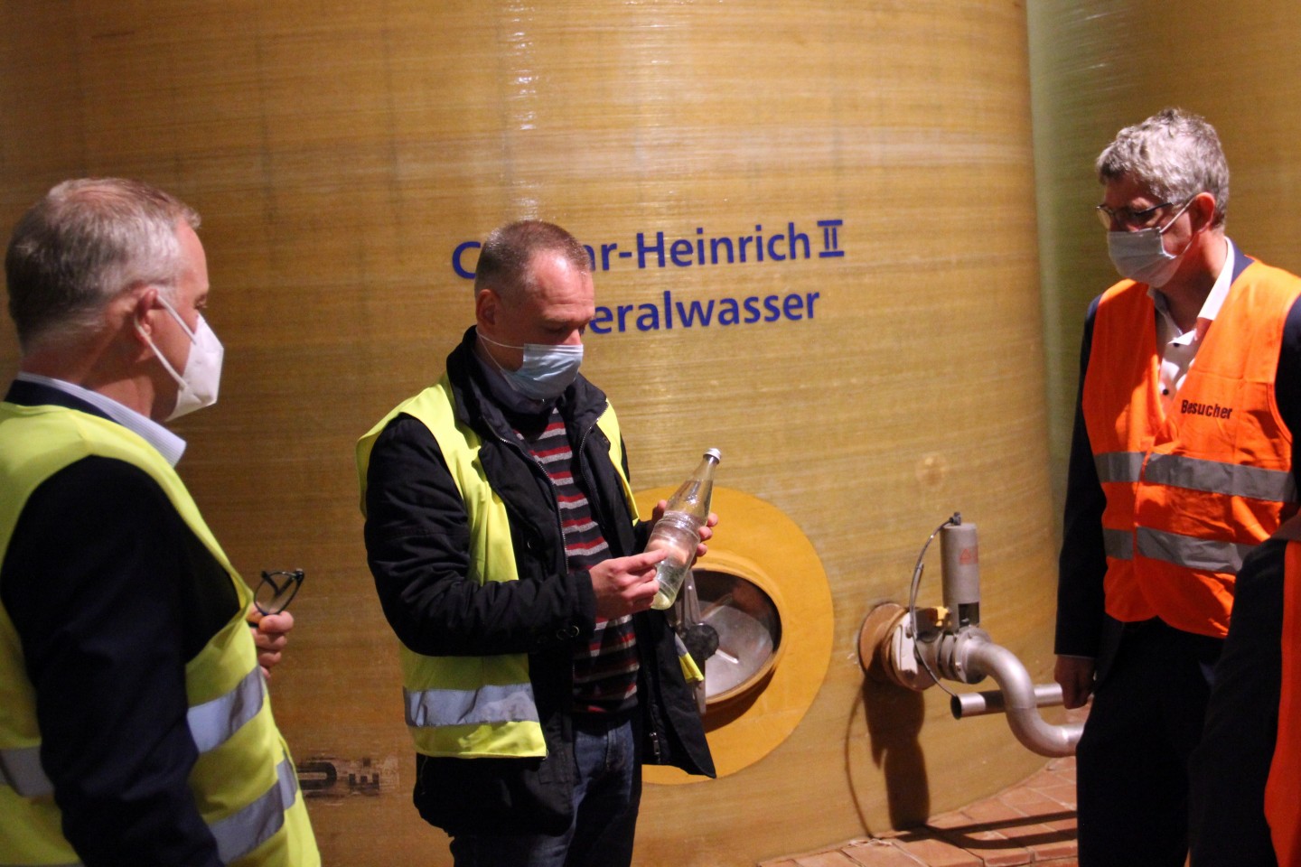 Foto 1: v.l.n.r: Rüdiger Uhle (Vertriebsleiter Bad Driburger Naturparkquellen), Michael Hielscher (Betriebsleiter) mit der klassischen Mineralwasserflasche – auch „Perlenflasche“ genannt – und MdB Chr