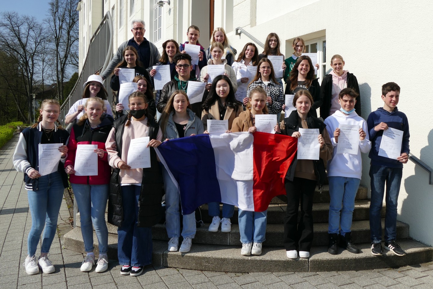 Das Titelbild zeigt die ausgezeichneten Schülerinnen und Schüler gemeinsam mit Französischlehrerin Vera Berlage (2. Reihe rechts außen) und Schulleiter Antonio Burgos (hinten links).