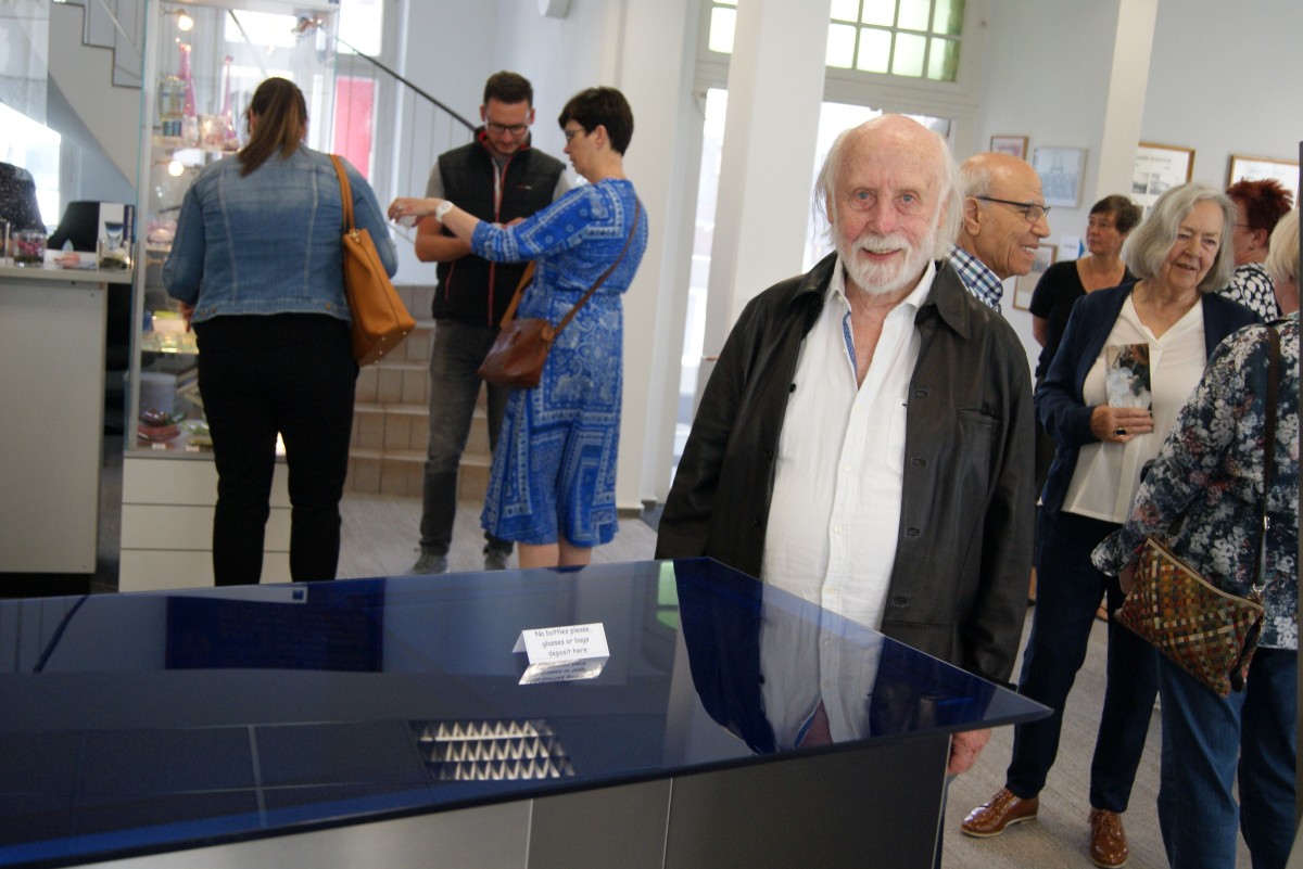 Paul Grohs präsentiert im Bad Driburger Glasmuseum einen faszinierenden Tisch mit einer großen blauen Glasplatte, die auf miteinander verschraubten Metallplatten ruht
